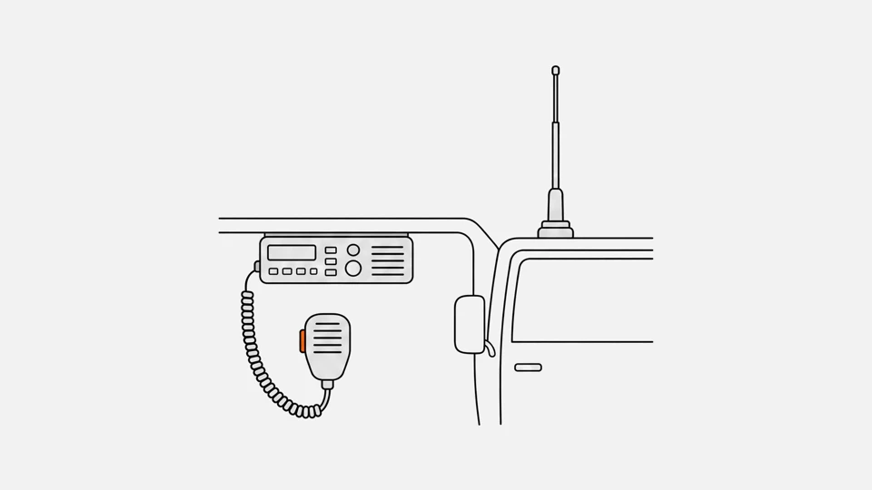 A CB radio under a truck dashboard, a hand microphone on a coiled cord and a whip antenna on the cab roof