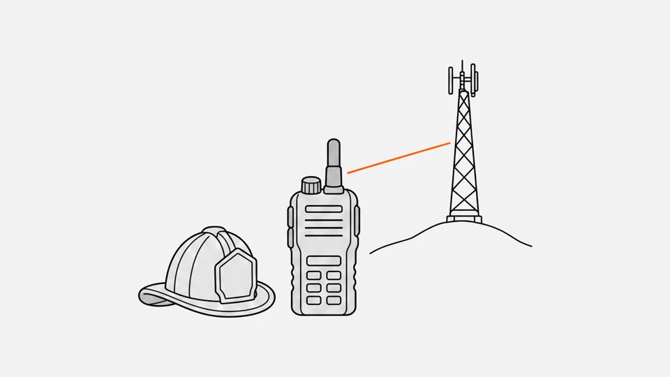 A firefighter helmet beside a rugged P25 handheld radio, its signal line reaching a repeater mast on a hill